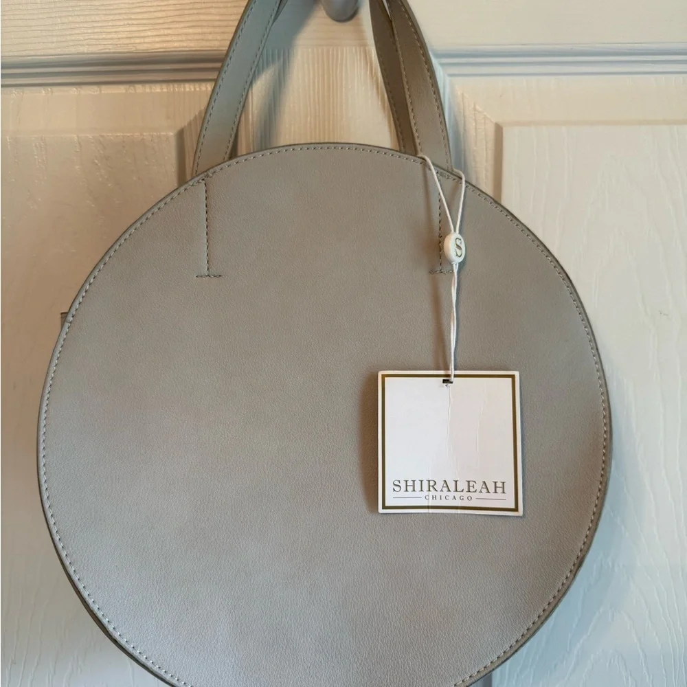 NWT Elegant Shira Leah Gray round leather handbag with a minimalist design.